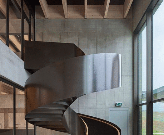 Escada metálica helicoidal com design exclusivo em ambiente sofisticado - a arte em aço da HBFER Estruturas Metálicas